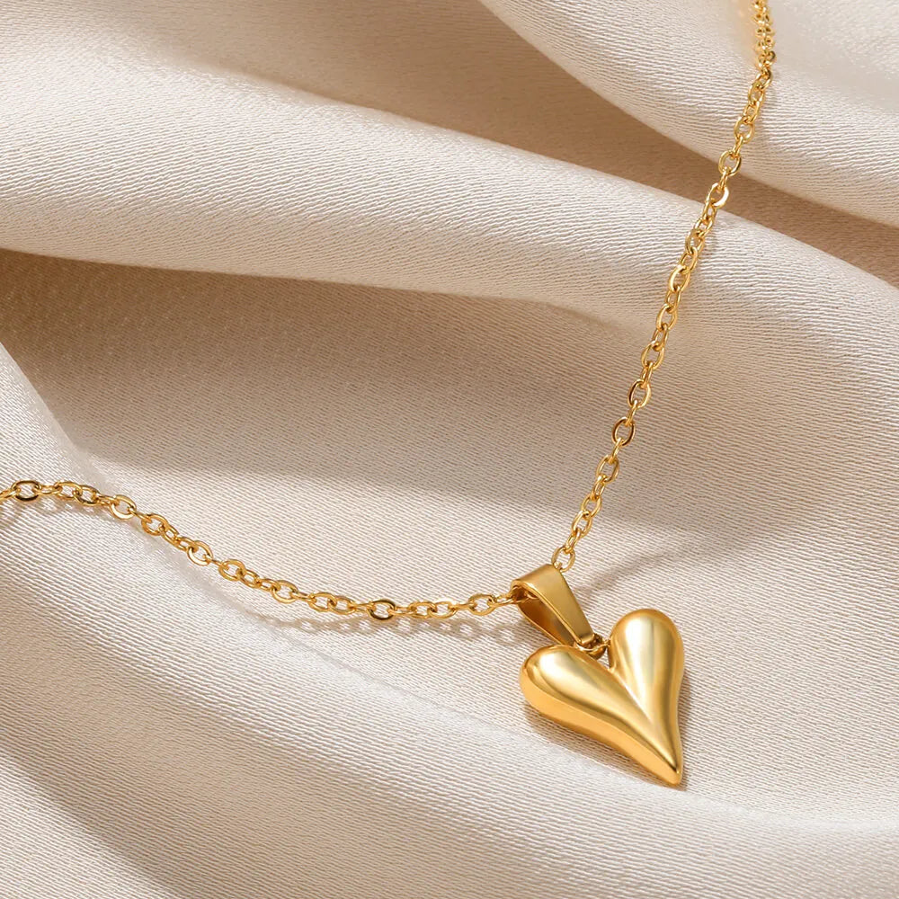 Goldene Herz-Halskette auf beigem Stoff, eleganter Schmuck, modisches Accessoire.