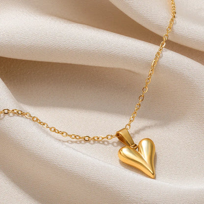 Goldene Herz-Halskette auf beigem Stoff, eleganter Schmuck, modisches Accessoire.