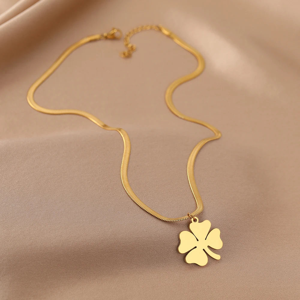 Goldene Halskette mit Kleeblatt-Anhänger auf beigem Hintergrund, Schmuck, Glücksbringer.