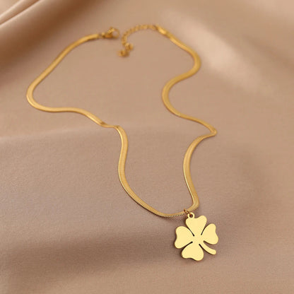 Goldene Halskette mit Kleeblatt-Anhänger auf beigem Hintergrund, Schmuck, Glücksbringer.