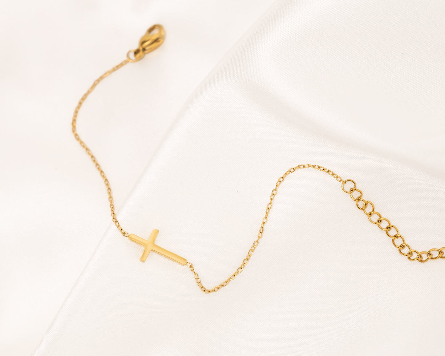 Goldenes Kreuzarmband auf Satin, filigran, Damen-Schmuck, modisch, elegant, Geschenkidee.