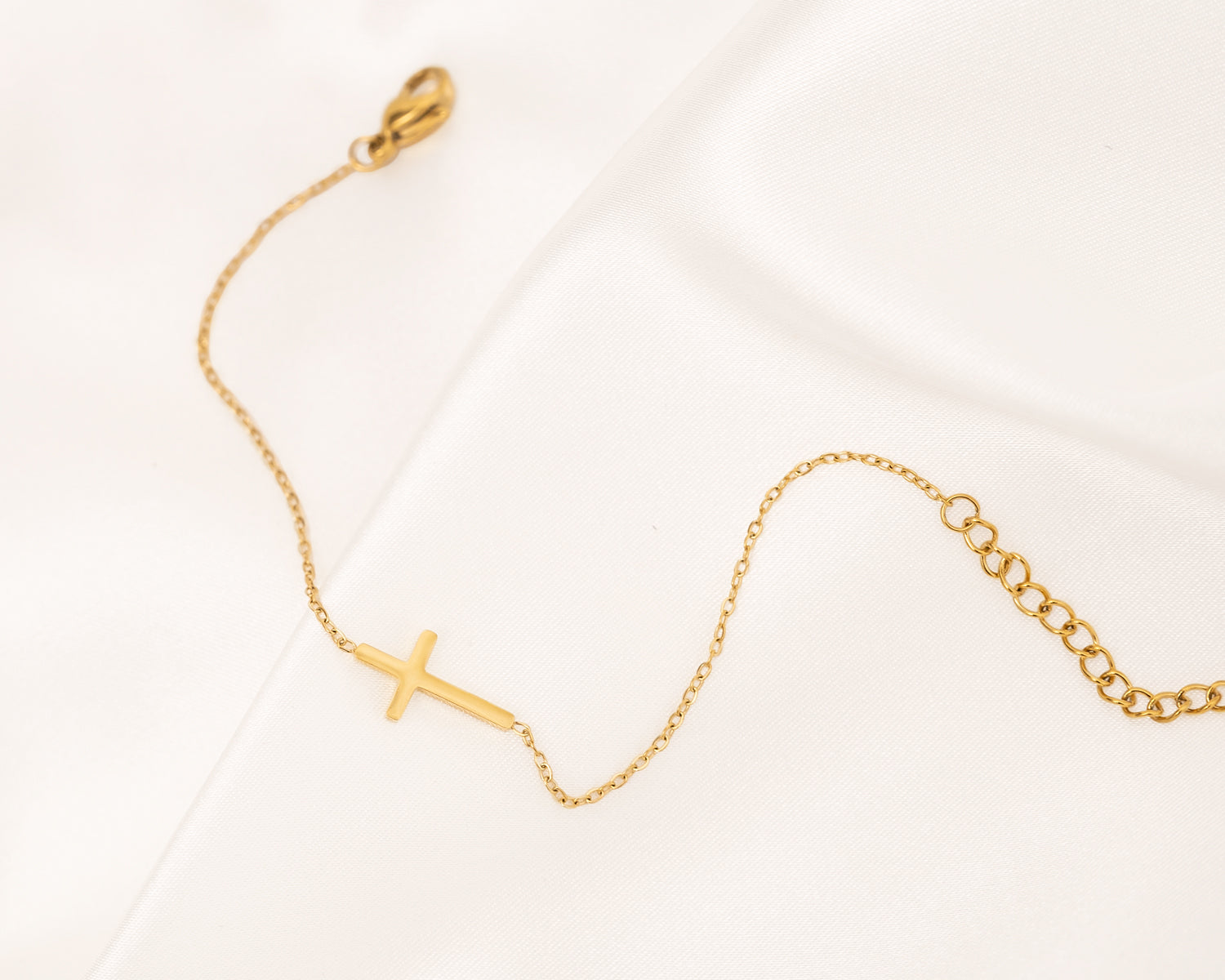 Goldenes Kreuzarmband auf Satin, filigran, Damen-Schmuck, modisch, elegant, Geschenkidee.