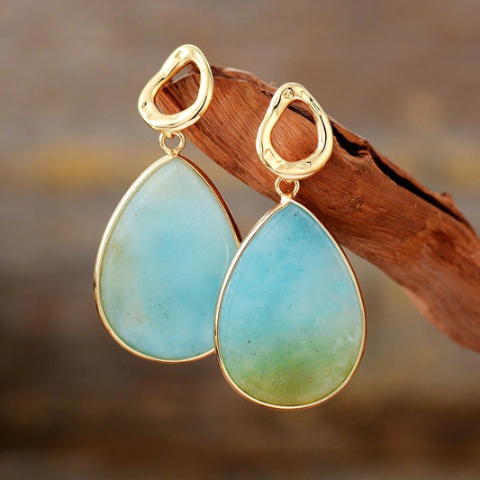 Goldene Ohrringe mit blauen Tropfenanhängern, eleganter Schmuck für Damen.