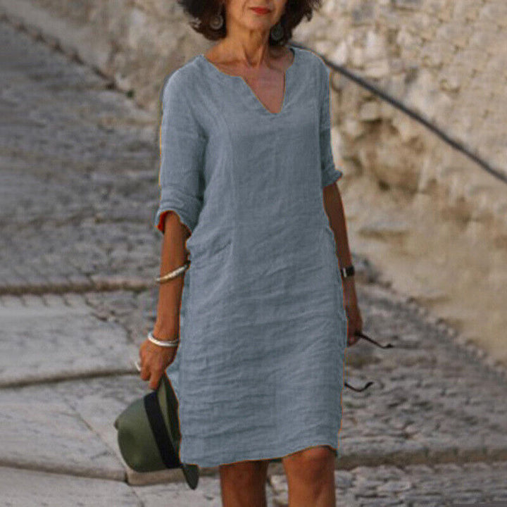 Frau in grauem Leinenkleid, V-Ausschnitt, Sommermode, lässig, stilvoll, Gehweg.