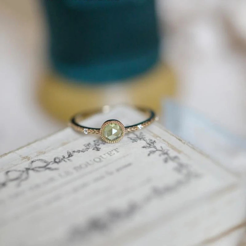 Goldener Ring mit grünem Edelstein, filigranes Design, Damen-Schmuck, elegantes Accessoire.