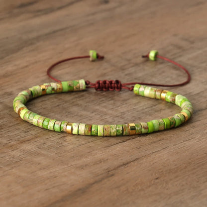 Grünes Perlenarmband aus Naturstein mit verstellbarem braunem Band auf Holzoberfläche.
