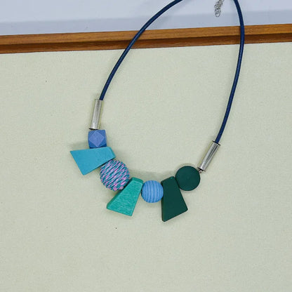 Bunte geometrische Halskette, handgefertigt, Holzperlen, blaues Band, modisches Accessoire.
