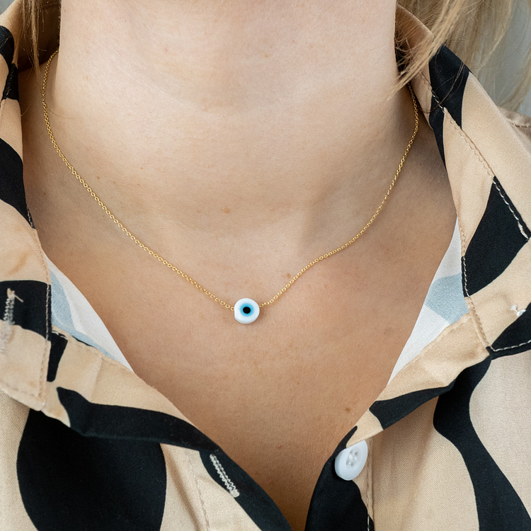 Goldene Halskette mit blauem Auge-Anhänger, modisches Accessoire, Nahaufnahme.