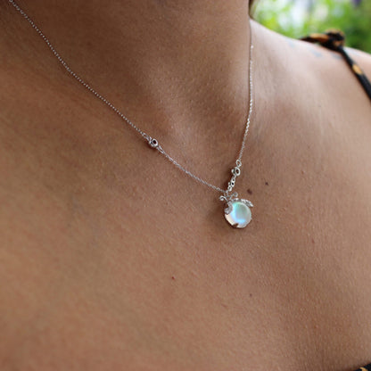 Silberne Halskette mit rundem, schimmerndem Anhänger auf Haut, eleganter Schmuck.
