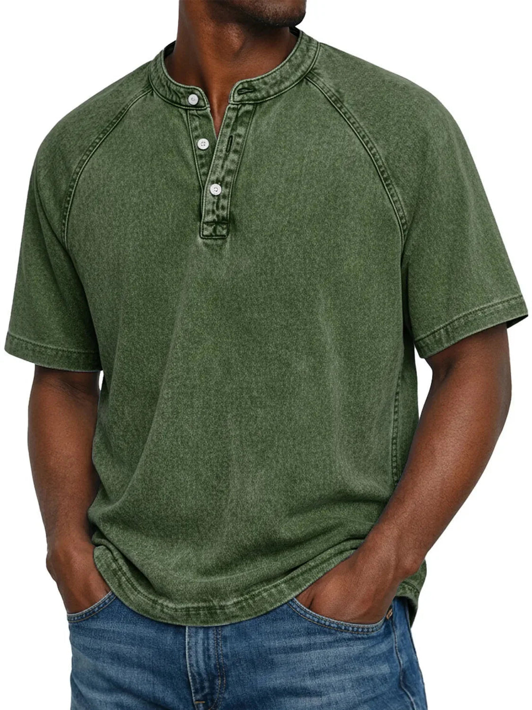 Mand i mørkegrøn vasket Henley-T-shirt med raglanærmer og tre knapper ved halsudskæringen, kombineret med jeans. 7