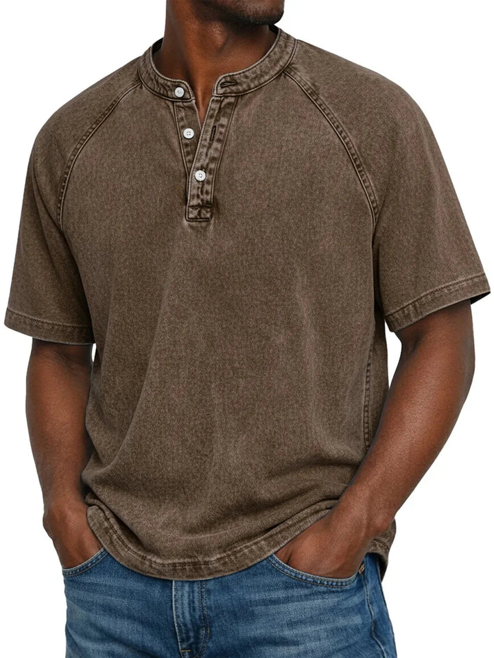 Mand i brun vasket Henley-T-shirt med raglanærmer og knaplukning, set forfra sammen med blå jeans. 8