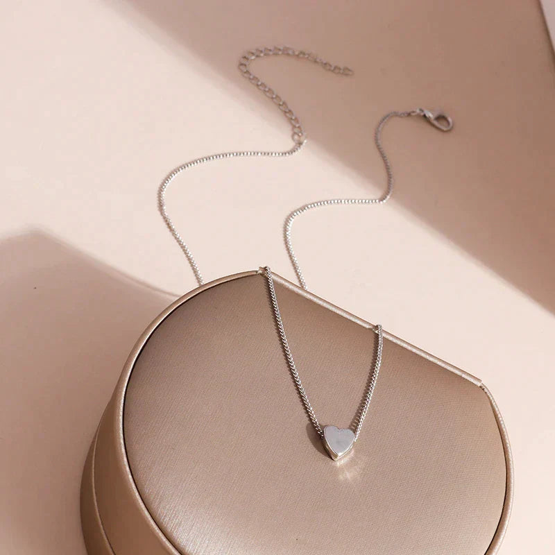 Silberne Herz-Halskette auf beigem Hintergrund, eleganter Schmuck, Damenaccessoire.