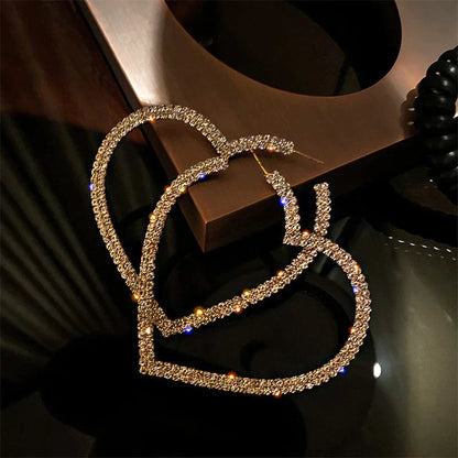 Goldene Herz-Ohrringe, funkelnde Strasssteine, modisches Schmuck-Accessoire, Damen-Mode.