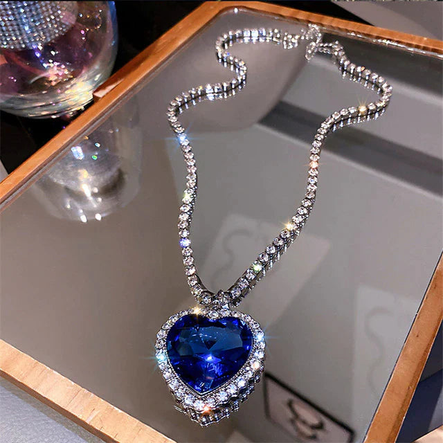 Herzförmiger blauer Diamantanhänger an silberner Halskette auf Spiegel, luxuriöser Schmuck.