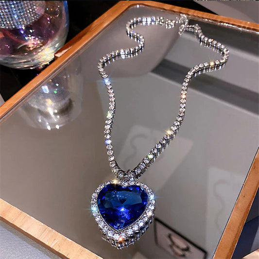 Herzförmiger blauer Diamantanhänger an silberner Halskette auf Spiegel, luxuriöser Schmuck.