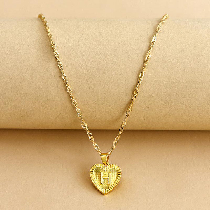 Goldene Herz-Halskette mit Buchstabenanhänger, gedrehtes Kettendesign, eleganter Schmuck.