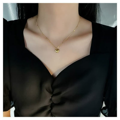 Goldene Herz-Halskette, zartes Design, Damenmode, eleganter Schmuck, schwarzes Kleid.
