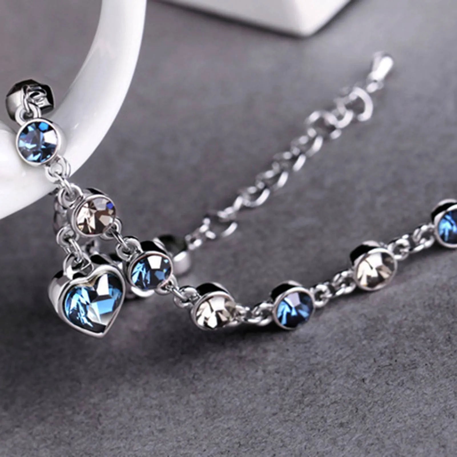 Silberarmband mit blauen und klaren Kristallen, Herzanhänger, eleganter Schmuck für Damen.