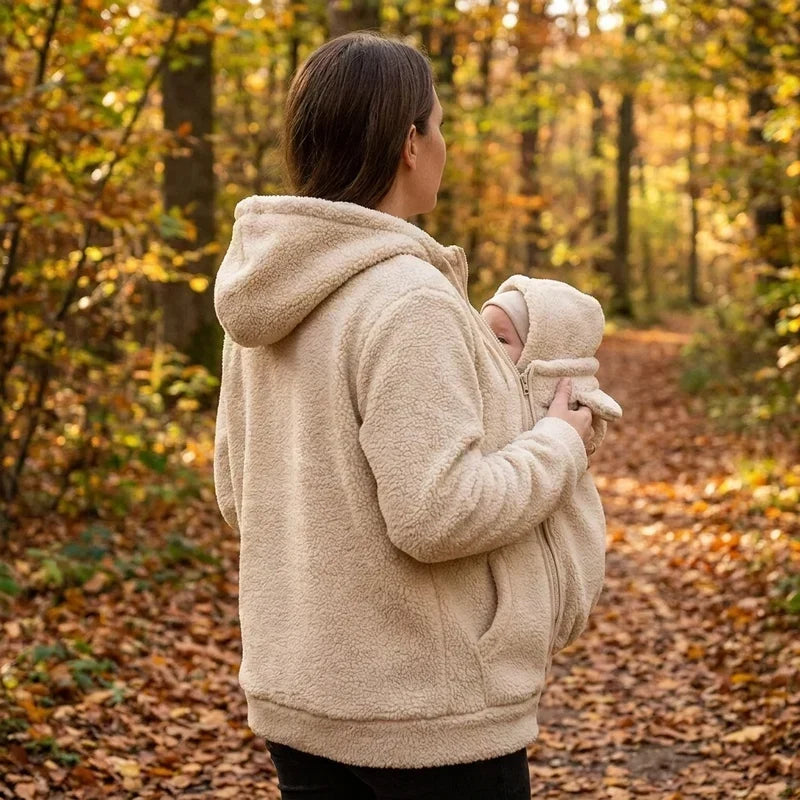 Kvinde set bagfra og fra siden i cremefarvet sherpa-trøje med hætte, mens hun bærer sin baby i skoven. 6