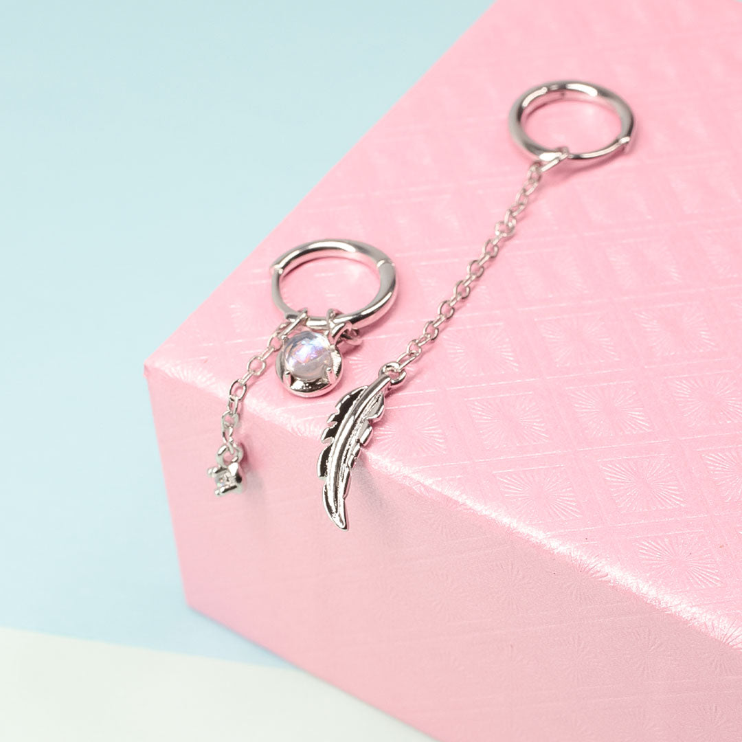 Silberne Ohrringe mit Federanhänger und Perle auf rosa Geschenkbox, modischer Schmuck.