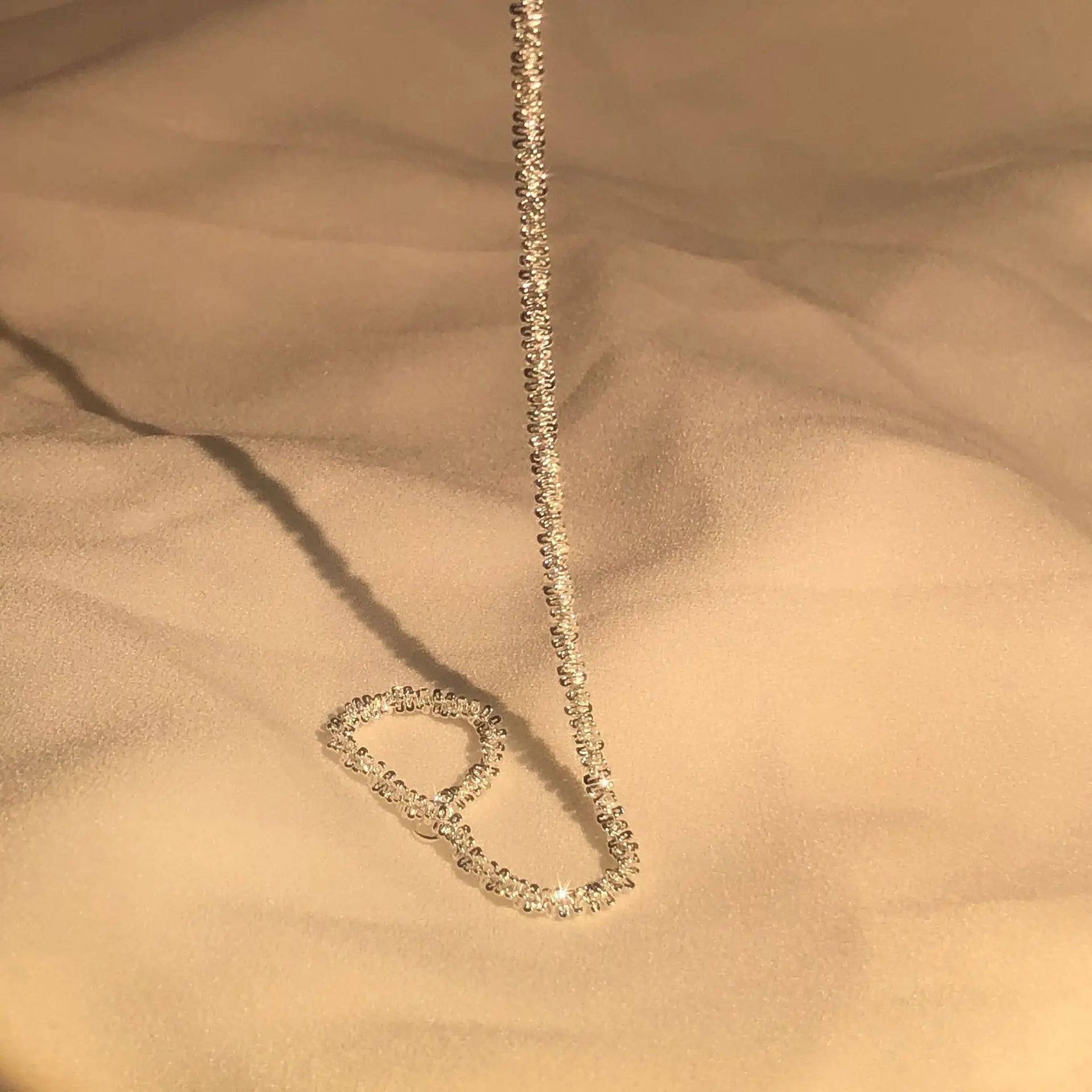 Goldene Halskette mit funkelnden Diamanten auf beigem Stoff, eleganter Schmuck für Damen.