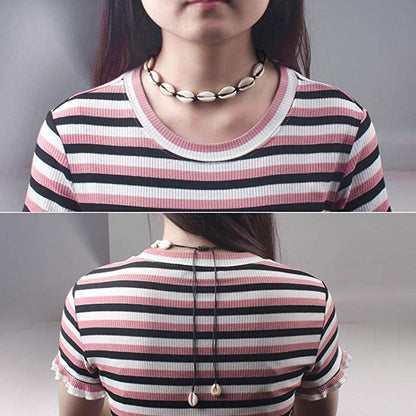 Frau mit gestreiftem Shirt trägt Muschel-Halskette, modisches Accessoire, Boho-Stil.