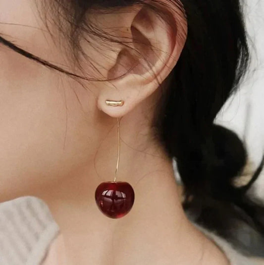 Frau mit Kirsch-Ohrring, rotes Harz, modisches Accessoire, eleganter Schmuck, Nahaufnahme.