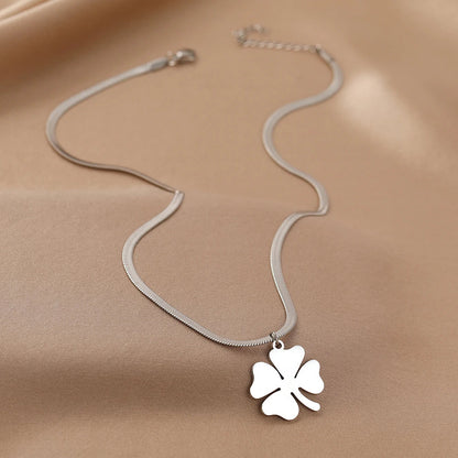 Silberne Halskette mit Kleeblatt-Anhänger auf beigem Hintergrund, Schmuck, Glücksbringer.