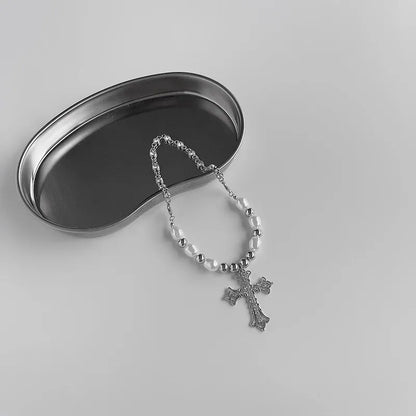 Silberne Kreuzkette mit Perlen auf Metalltablett, religiöser Schmuck, minimalistisch.