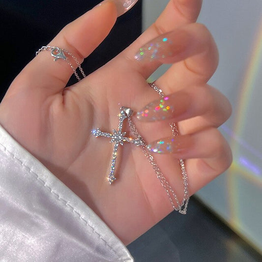 Silberne Kreuzkette mit Strasssteinen, funkelnde Nageldesigns, elegante Schmuckmode.