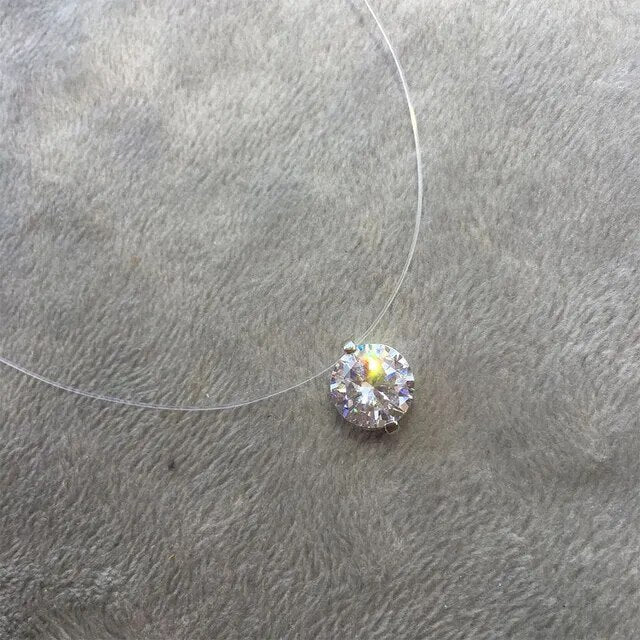 Transparente Halskette mit rundem Diamantanhänger auf grauem Hintergrund, eleganter Schmuck.