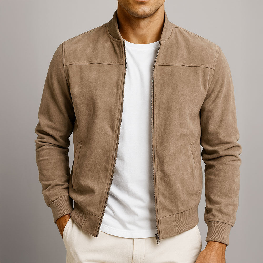 Model i beige jakke med åben lynlås over hvid t-shirt, den ene hånd i lommen, set forfra mod grå baggrund. 1