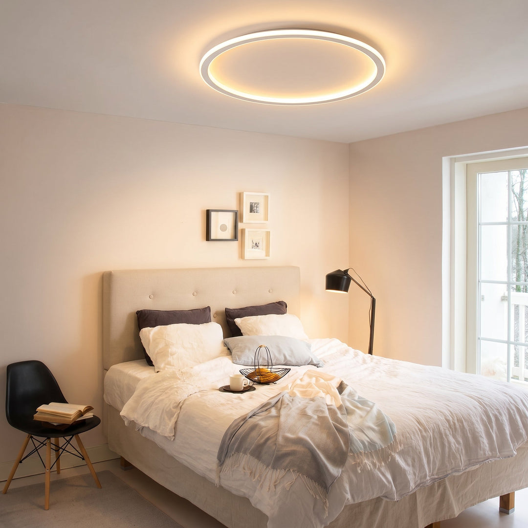 Tændt loftslampe over en dobbeltseng i et soveværelse med lyse vægge, sengetøj og gulvlampe. 9