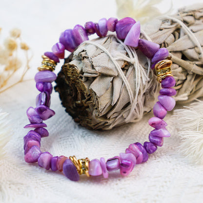 Lila Edelstein-Armband mit goldenen Akzenten auf weißem Hintergrund, Schmuck, Modeaccessoire.