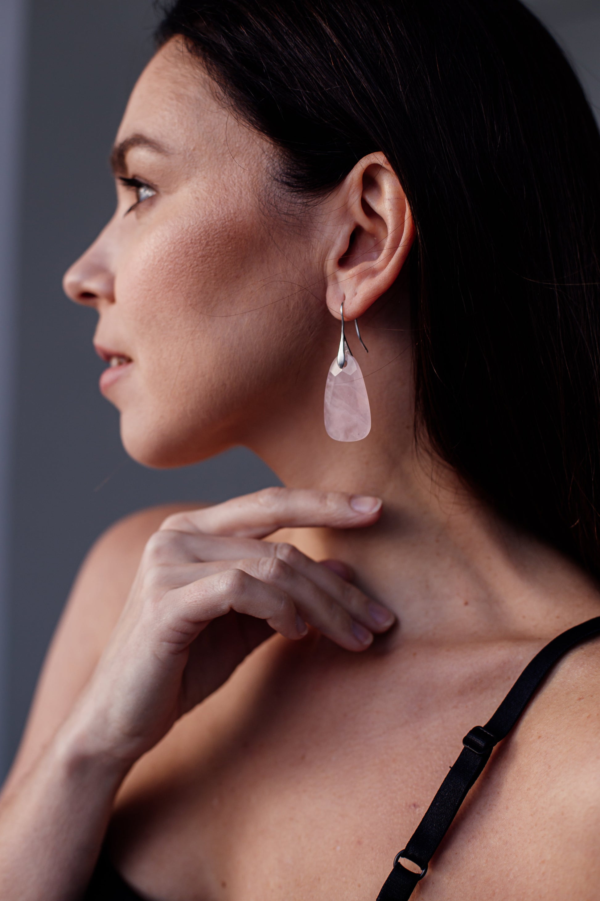 Frau mit rosa Ohrring, Silberhaken, Nahaufnahme, modisches Accessoire, eleganter Schmuck.