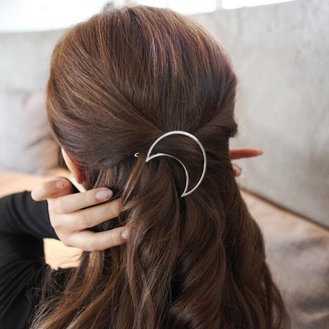 Frau mit braunem Haar trägt silberne Mond-Haarspange, modisches Accessoire, eleganter Stil.