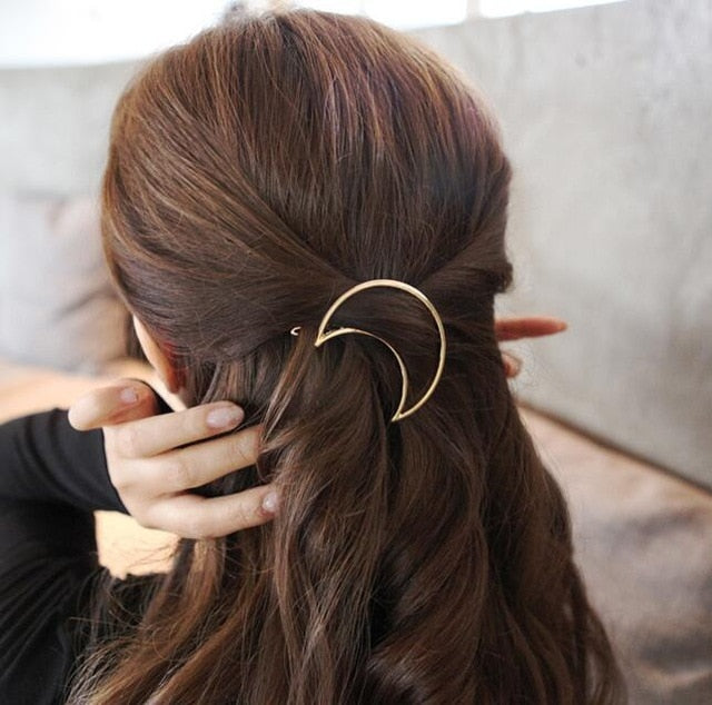 Frau mit braunem Haar und goldener Halbmond-Haarspange, elegantes Accessoire, Frisur.