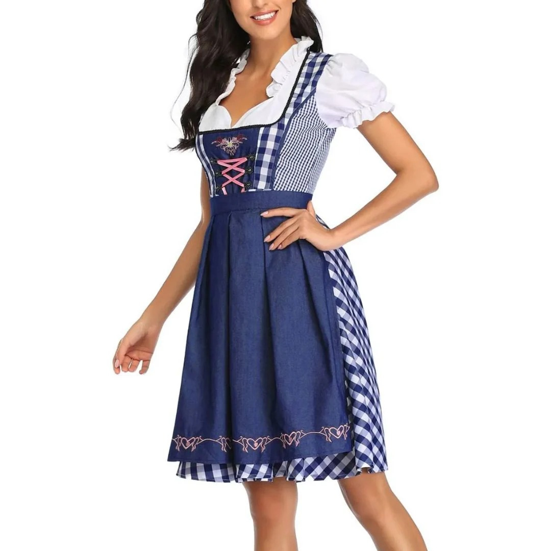 Model i dirndl med mørkeblåt forklæde og blå-hvid tern, hånd i siden, set lidt fra siden med detaljer i snøreliv. 6