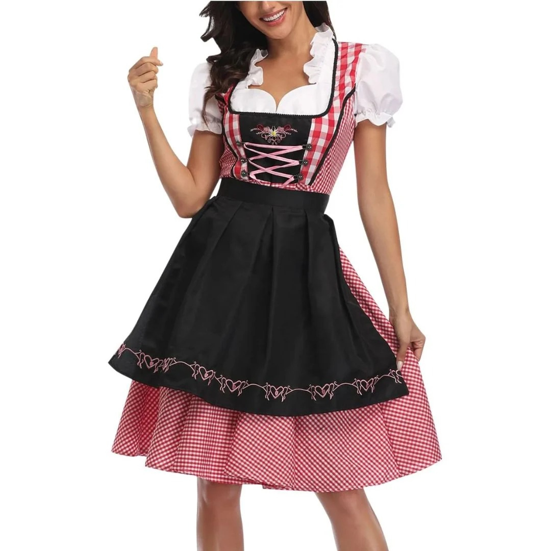 Model i rød-hvid tern dirndl med sort forklæde med broderet hjertekant, pink snøring og hvide pufærmer, set forfra. 1