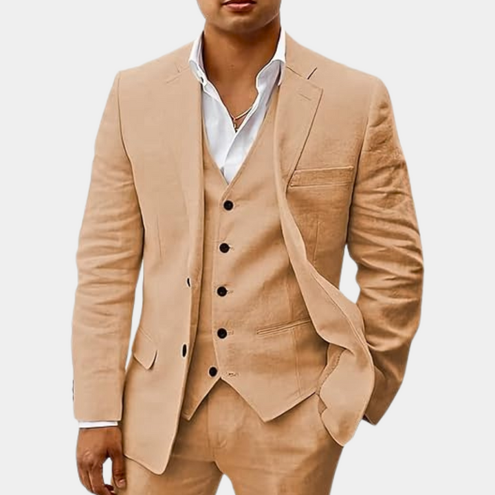 Model i sandfarvet beige tredelt jakkesæt med sorte knapper på vesten og hånden i lommen. 3